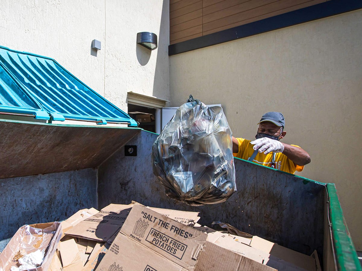 Restaurant employee throwing trash into a dumpster