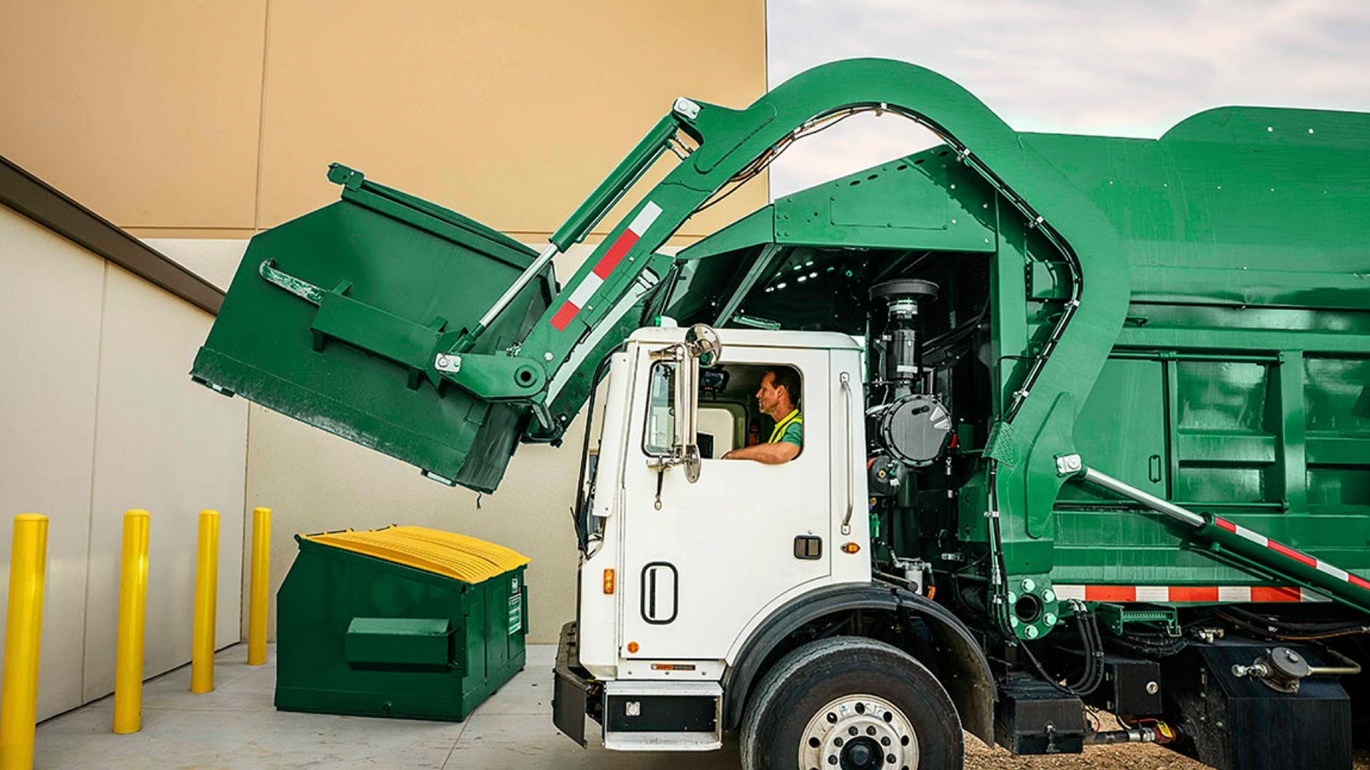 a garbage truck picking up a dumpster